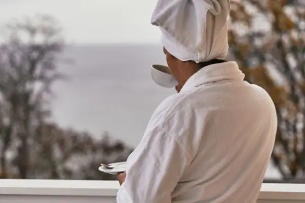SPA Eine Person im weißen Bademantel mit einem Handtuch auf dem Kopf und einer Tasse Tee.