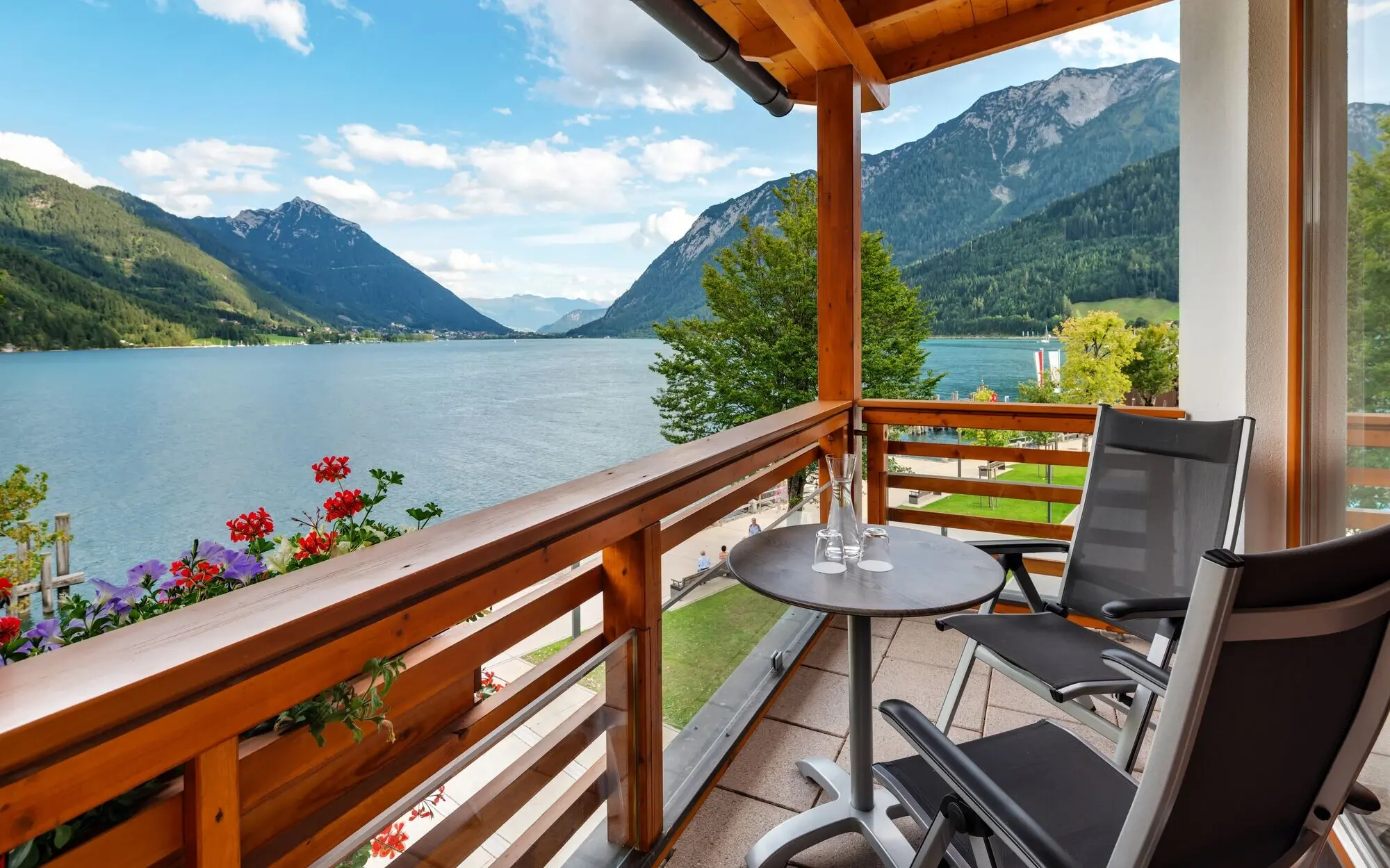 Balkon mit Tisch und Stühlen mit Blick auf den Achensee und Berge.