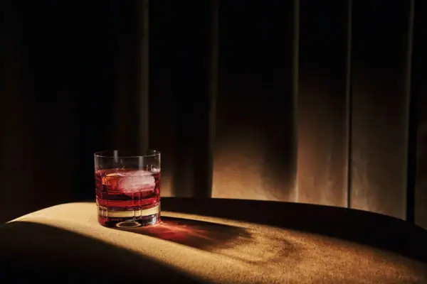 Ein Glas mit roter Flüssigkeit und Eis auf einem Tisch.