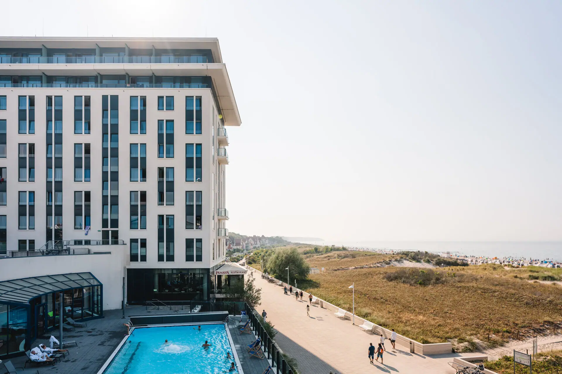 Ein Gebäude mit einem Pool und vorbeigehenden Menschen.