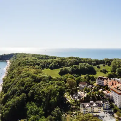aja Nordperd & Villen Göhren Landschaft mit Bäumen, Gebäuden und Küste im Hintergrund.