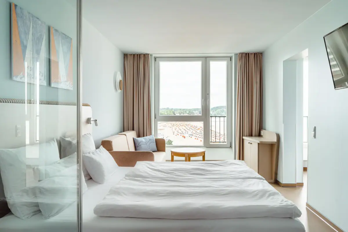 aja Travemünde Zimmer Ein Zimmer mit einem Bett, einem Stuhl und einem Tisch.