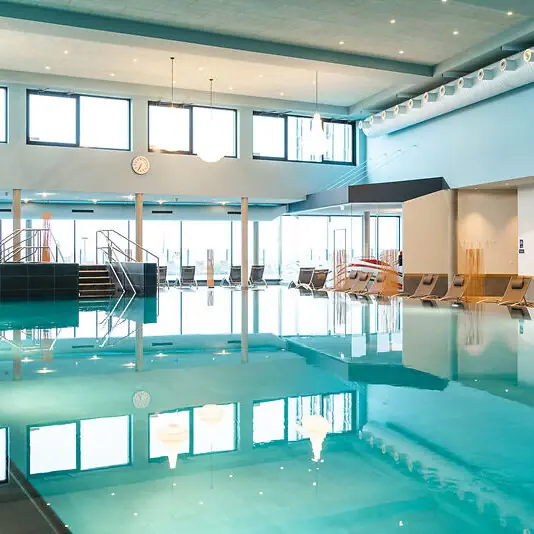 Großes Hallenbad mit Stühlen und Treppe.