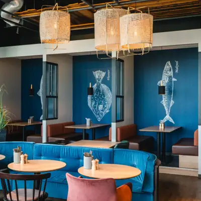 Restaurant im aja Warnemünde Ein Raum mit Tischen und Stühlen.