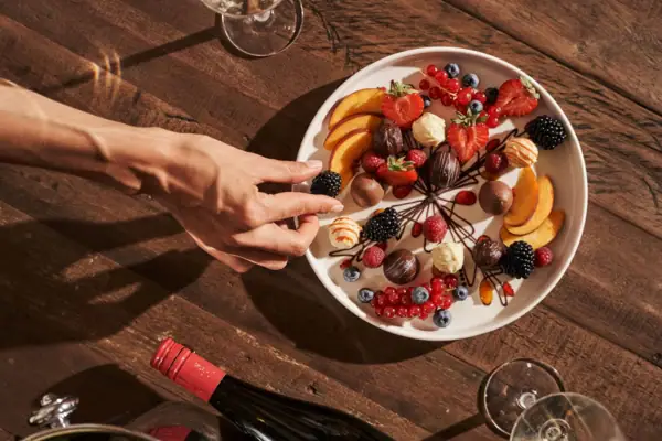 Dessert Eine Hand greift nach einem Teller mit Obst.