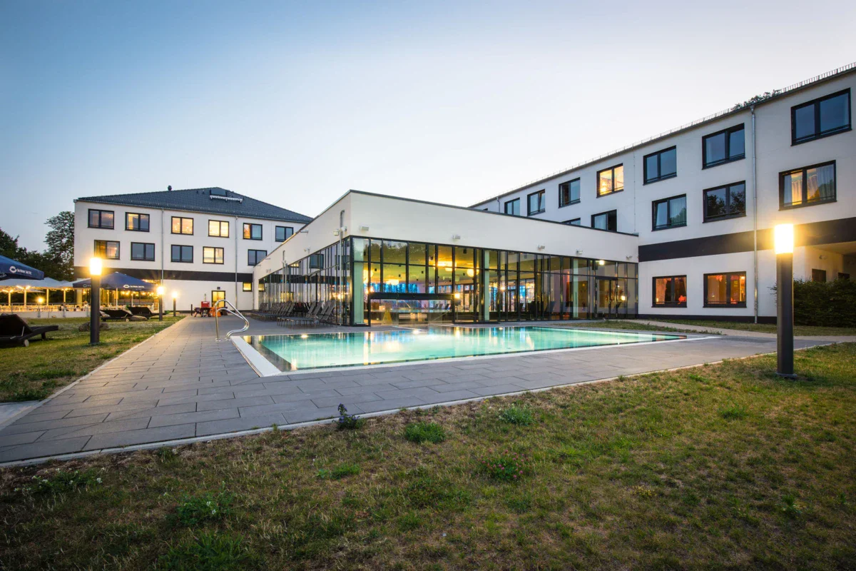 Ein Hotelgebäude mit einem Swimmingpool und Rasen.