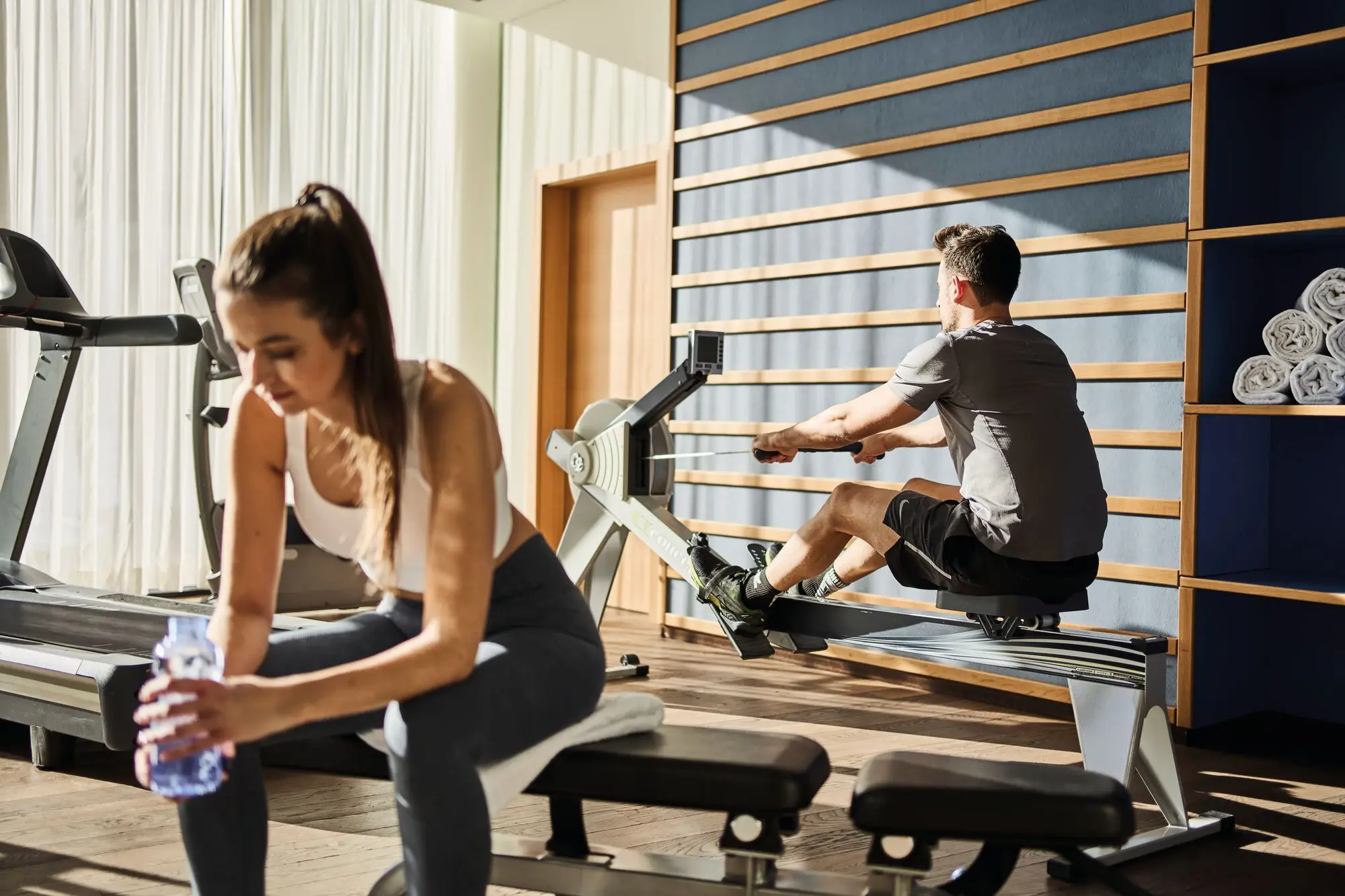 Ein Mann und eine Frau trainieren an Fitnessgeräten in einem Fitnessstudio.