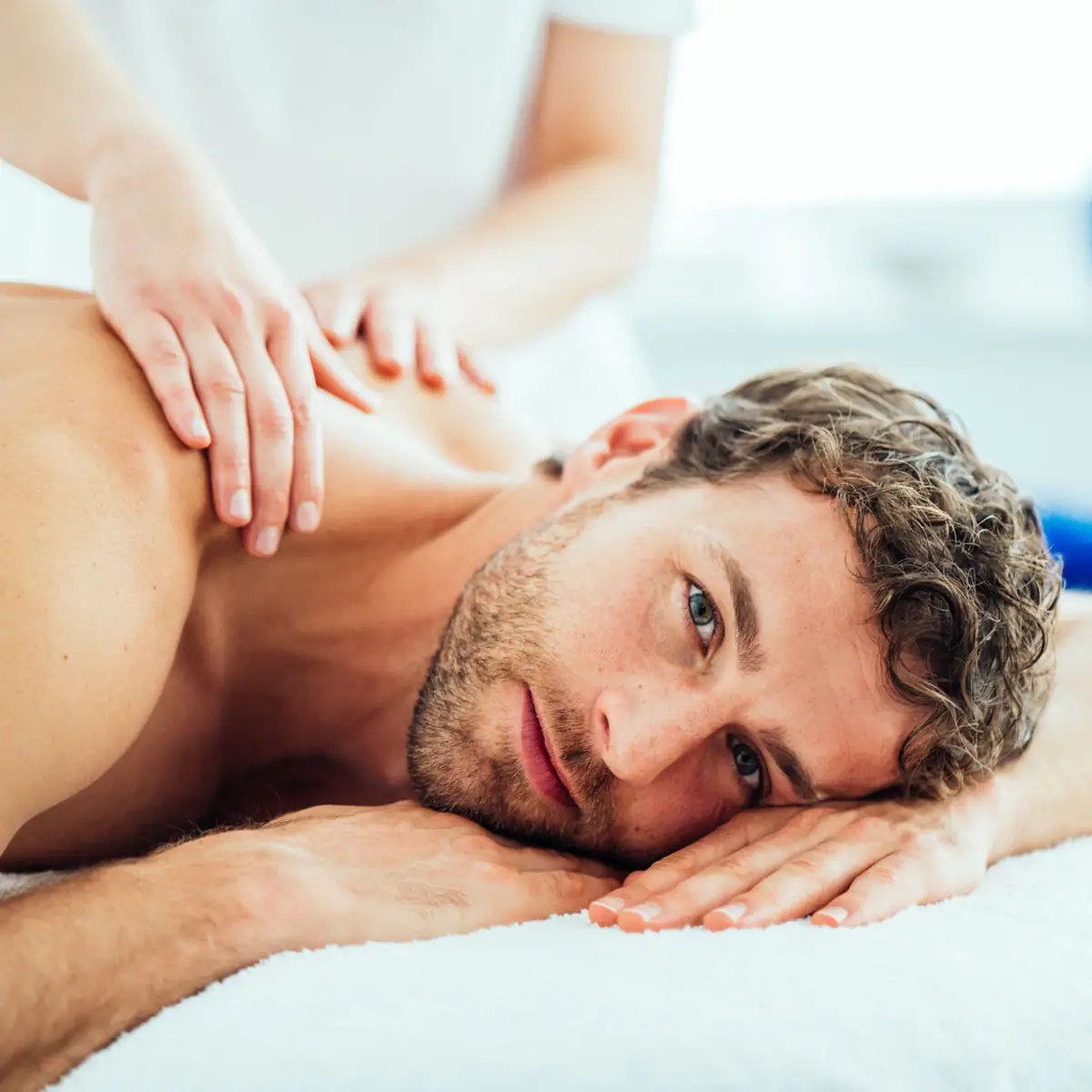 Entspannung bei aja Ein Mann liegt auf einem Massagetisch und wird am Nacken massiert.