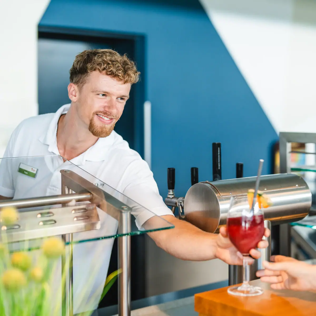 Ein Mann reicht einem Kunden ein Getränk.