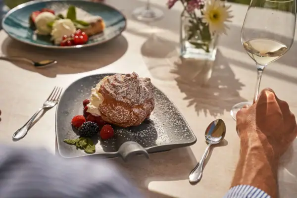 Ein Teller mit Dessert und Beeren neben einem Glas Wein.