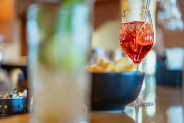 Cocktail Ein Glas mit roter Flüssigkeit und Strohhalm neben einer Schale Chips.