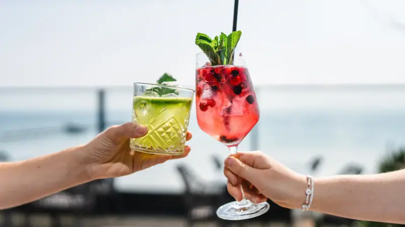 Drinks Ein Paar Hände hält Cocktails mit Erdbeergarnitur.