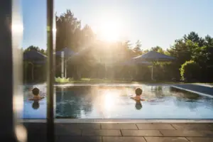 Ein Mensch schwimmt in einem Außenpool bei Sonnenschein.