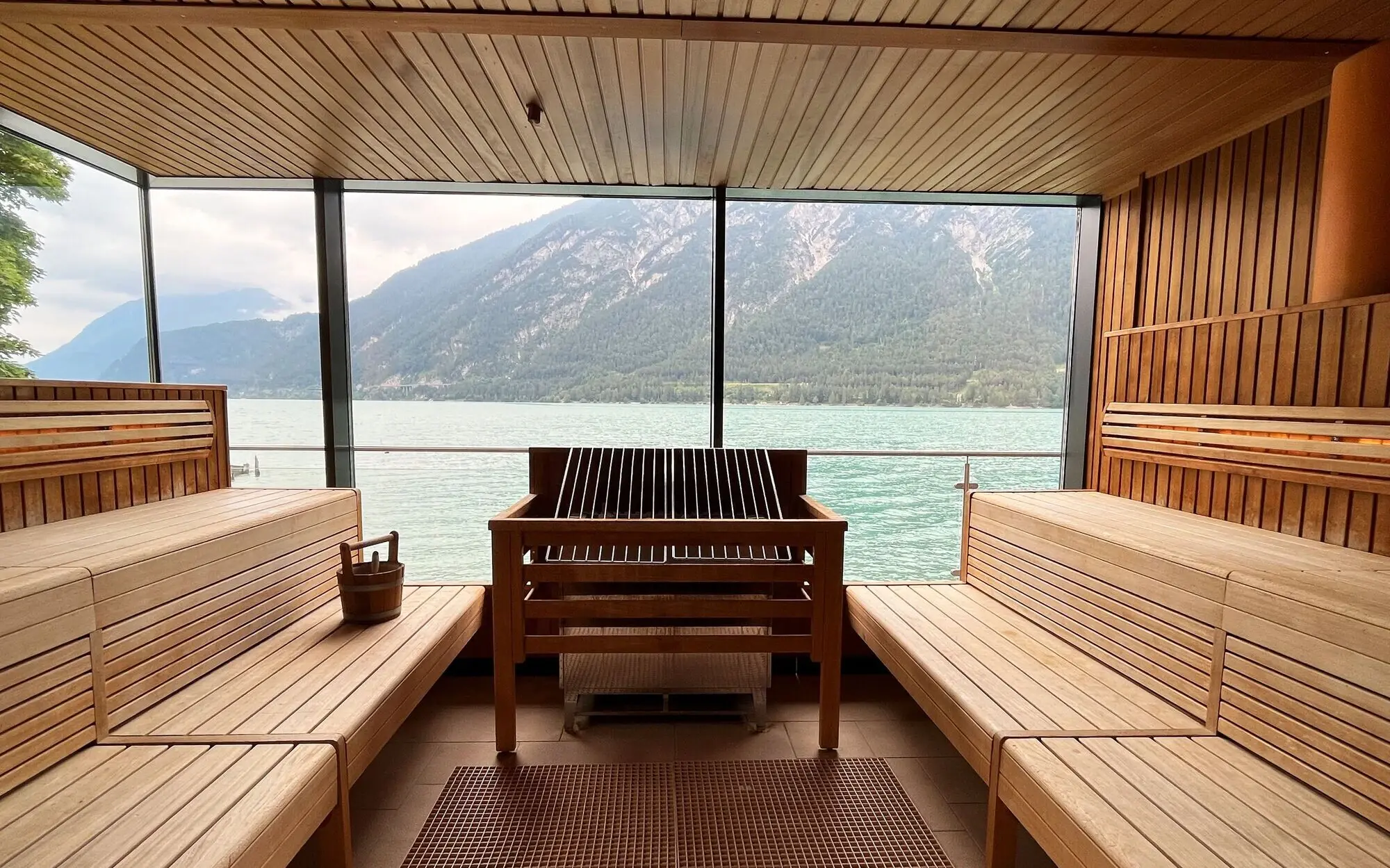 Große Panoramasauna mit Blick auf Wasser und Berge, ausgestattet mit Holzbänken.