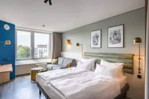 Zimmer im aja Warnemünde Ein Raum mit einem Doppelbett, Bildern an der Wand und einem Sofa.