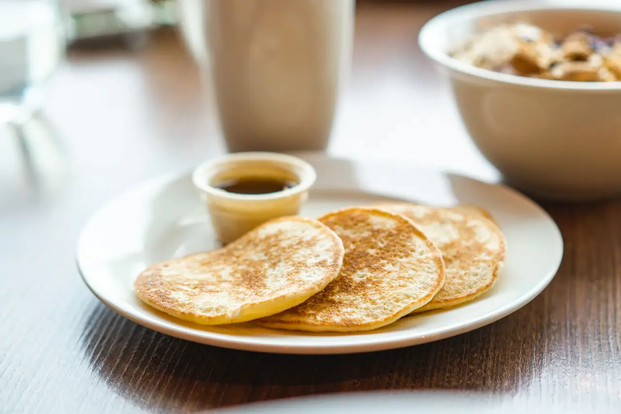 Ein Teller mit Pfannkuchen und eine Tasse Sirup.