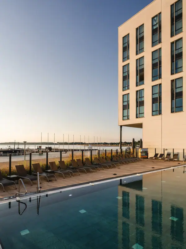 Ein Pool mit Liegestühlen und einem Gebäude im Hintergrund.