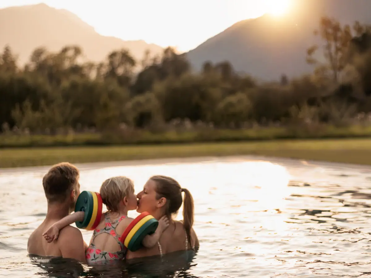 Eltern mit einem Kind im aja Familienhotel in Bayern in Ruhpolding, die im Außenpool schwimmen.