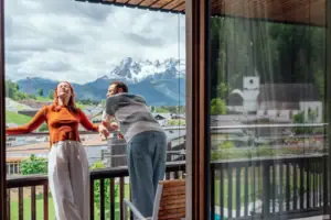 Ein Mann und eine Frau stehen auf einer Veranda und blicken auf Berge.