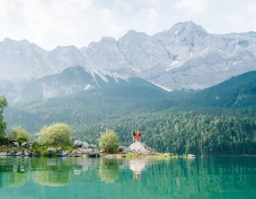 Eibsee Zwei Personen stehen auf einem Felsen vor einem See.