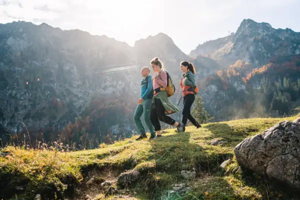 Eine Gruppe von Menschen beim Wandern auf einem Hügel mit Bergen im Hintergrund.