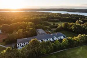 aja Bad Saarow Ein Gebäude umgeben von Bäumen und einem Gewässer.