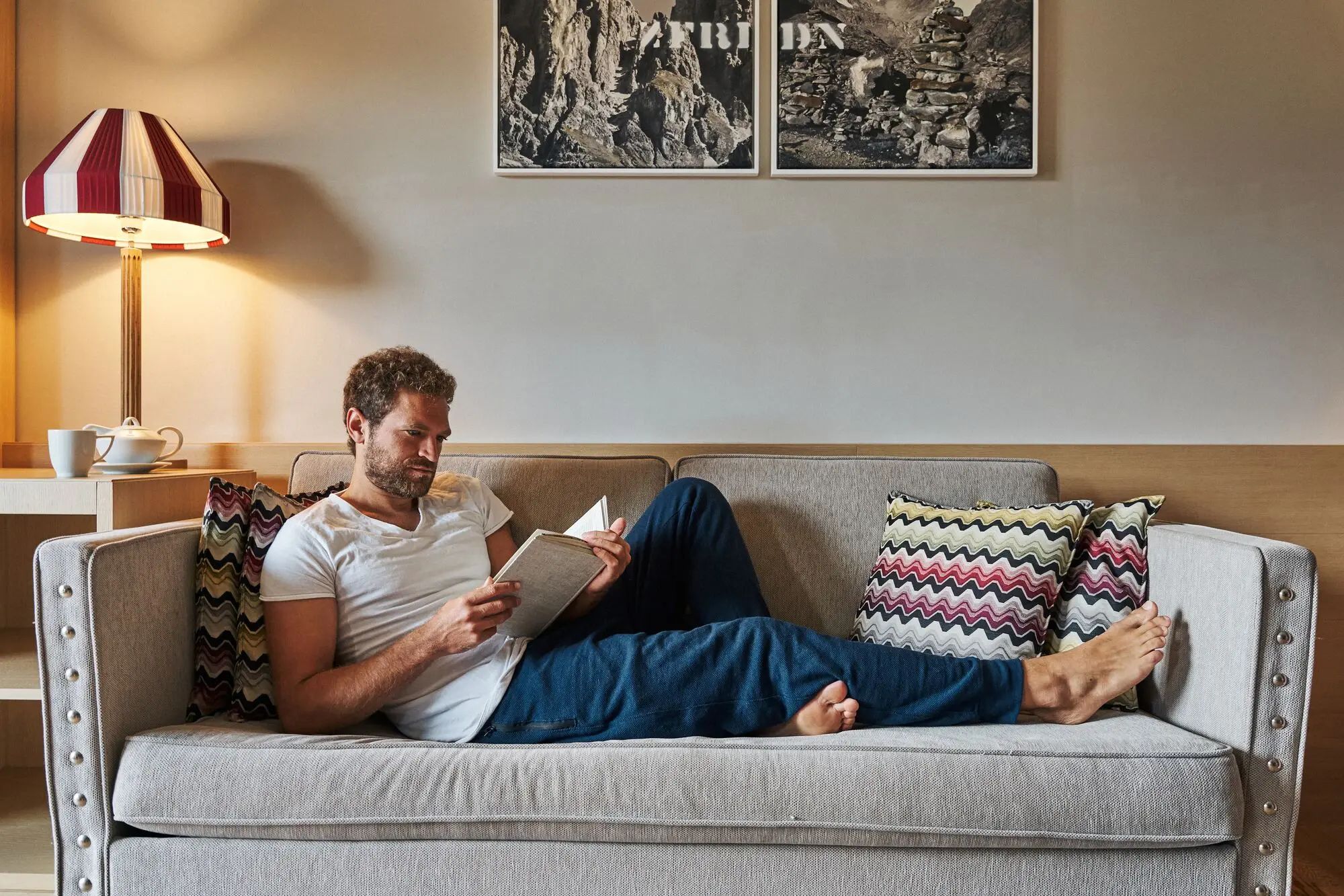 Ein Mann liest ein Buch auf einem Sofa.