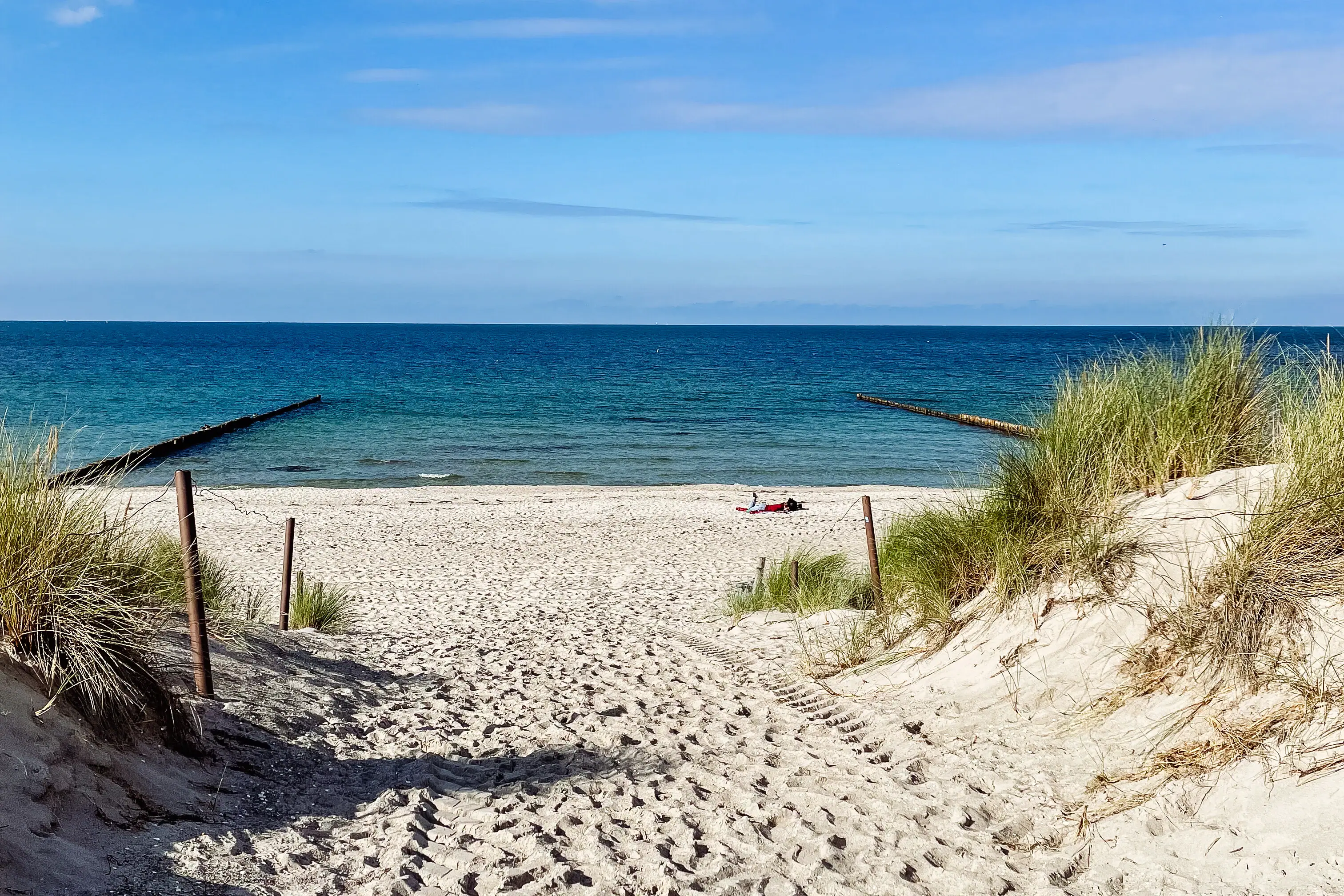 Sandstrand mit Gras und blauem Wasser