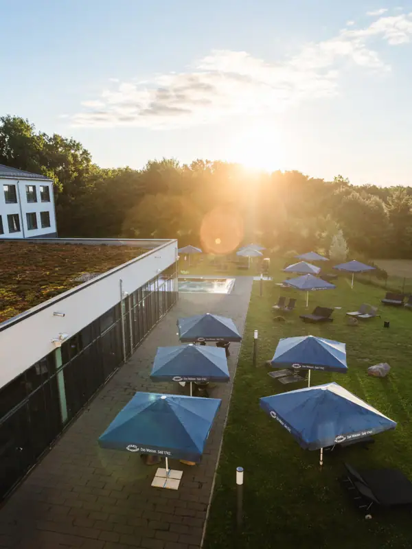 Ein Gebäude mit Sonnenschirmen und Stühlen auf einer Rasenfläche.