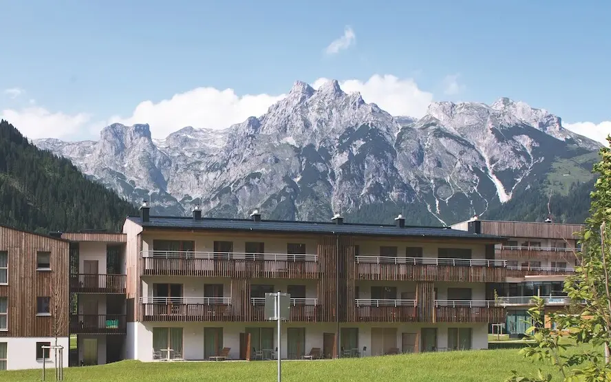 Building with lawn and mountain backdrop.