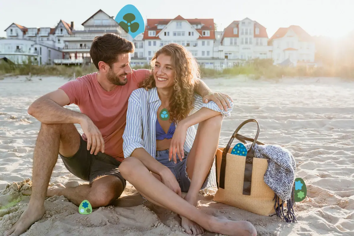 Ein Mann und eine Frau sitzen lächelnd am Strand.