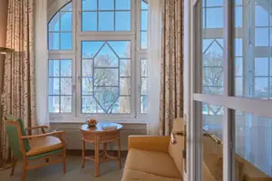 Wohnzimmer mit Couch und Tisch, Fenster im Hintergrund.