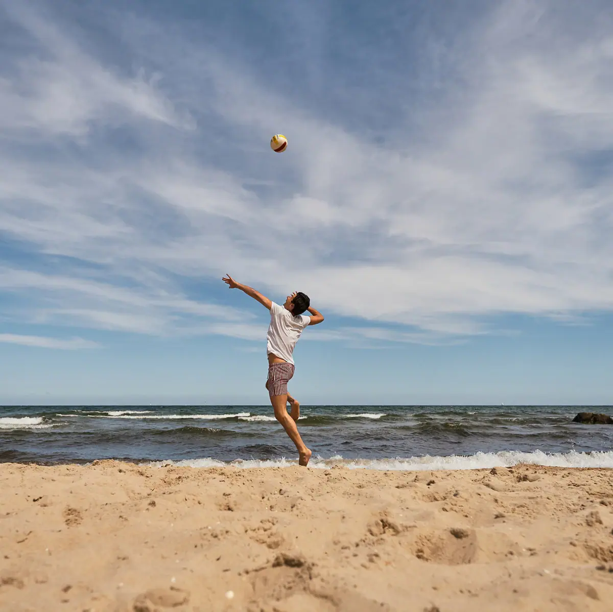 Volleyball am Strand Eine Person am Strand wirft einen Ball.