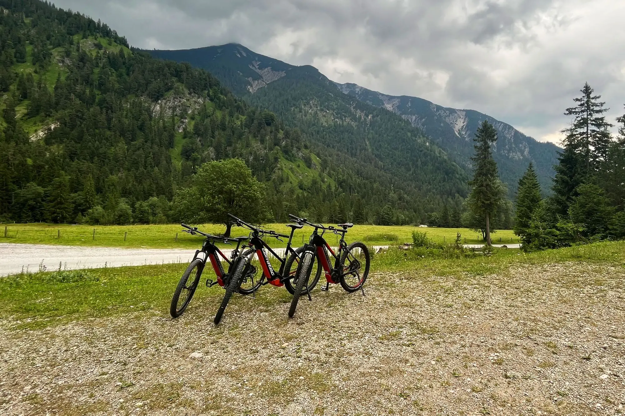 E-Bikes in den Bergen Eine Gruppe von Fahrrädern auf einem Kiesweg mit Bergen im Hintergrund.