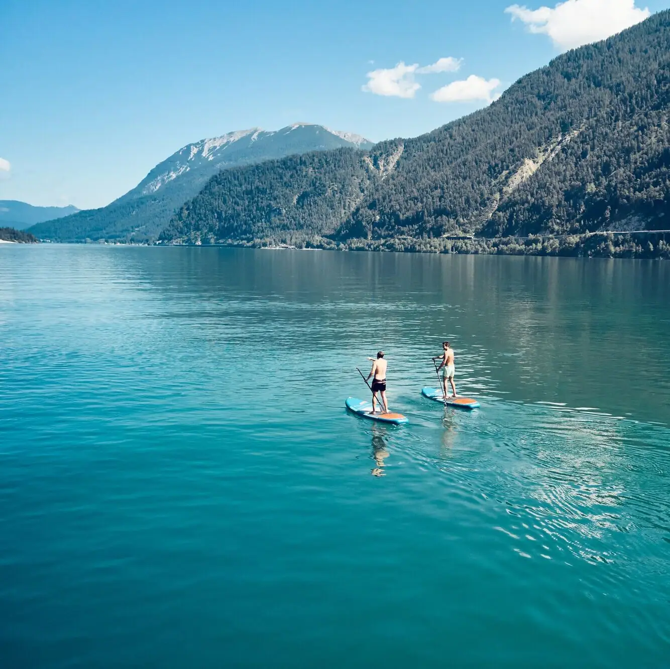 Zwei Personen auf Paddleboards auf einem See