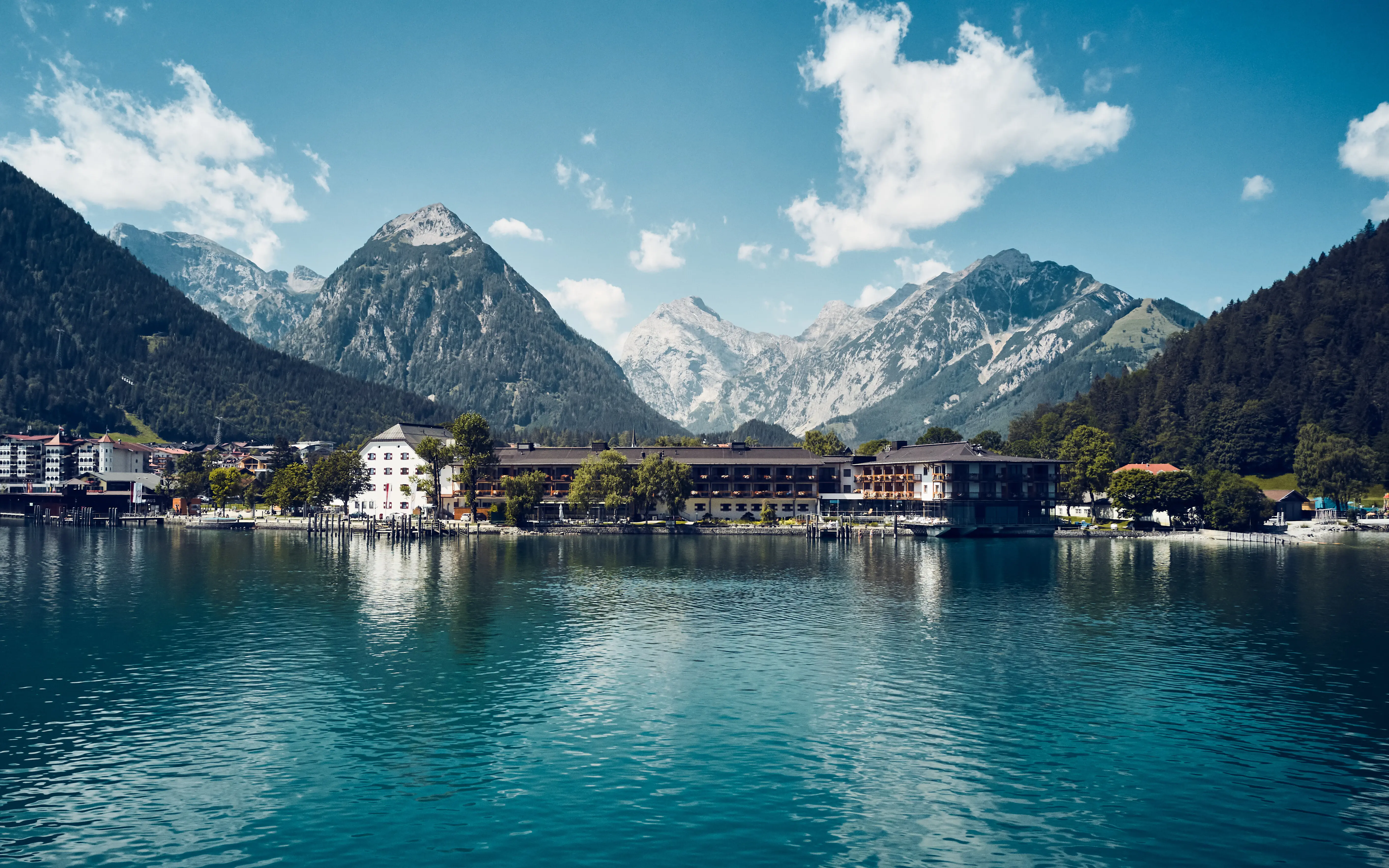 Bergsee mit Gebäude und Bergen im Hintergrund