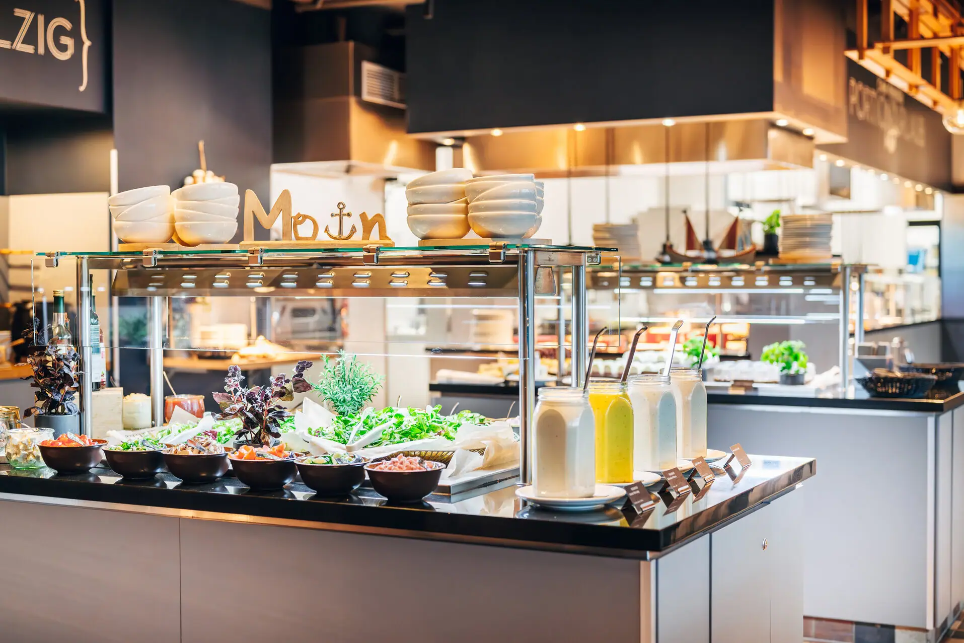 Theke mit Salaten und Gläsern gefüllt mit verschiedenen Dressings.