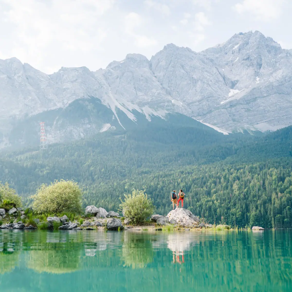 Menschen stehen auf einem Felsen vor einem See.