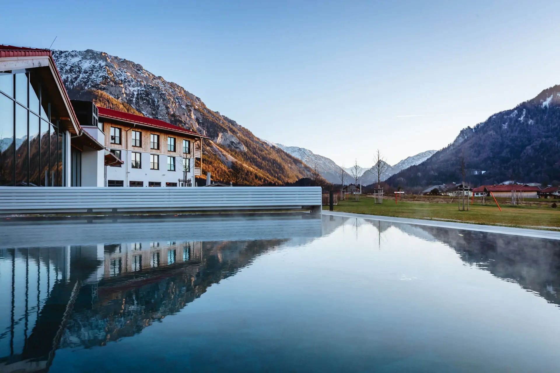 Außenansicht eines Pools mit Spiegelung eines Gebäudes im Hintergrund.