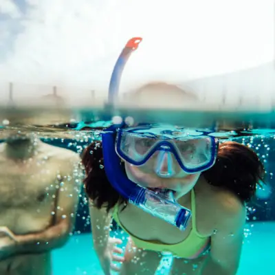 Ein Mädchen in Badeanzug und Schwimmbrille unter Wasser.