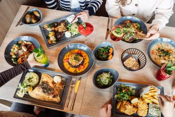 Bar Food Eine Gruppe von Menschen sitzt an einem Tisch mit Tellern voller Essen.