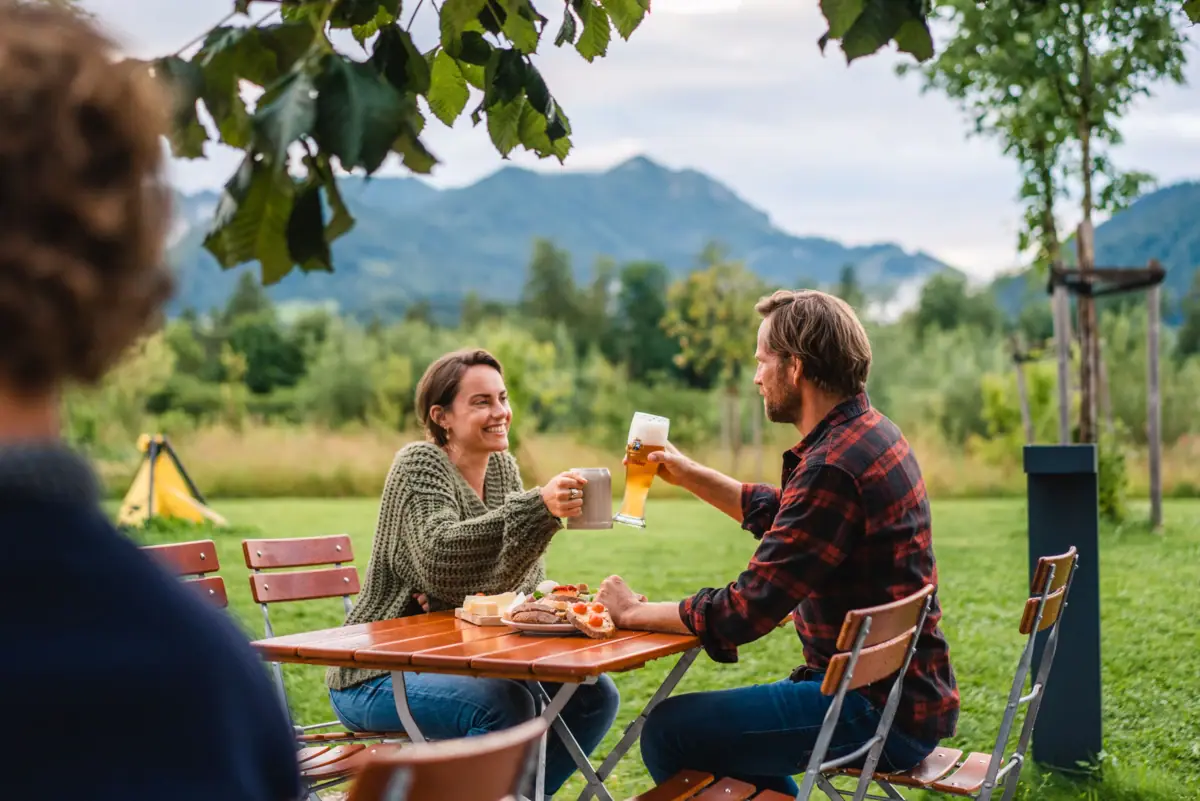 Ein Mann und eine Frau sitzen im Biergarten vom aja Ruhpolding.