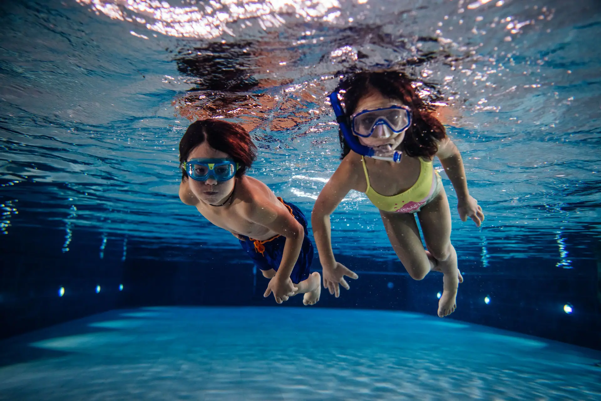 Mehrere Personen schwimmen unter Wasser im Schwimmbecken.