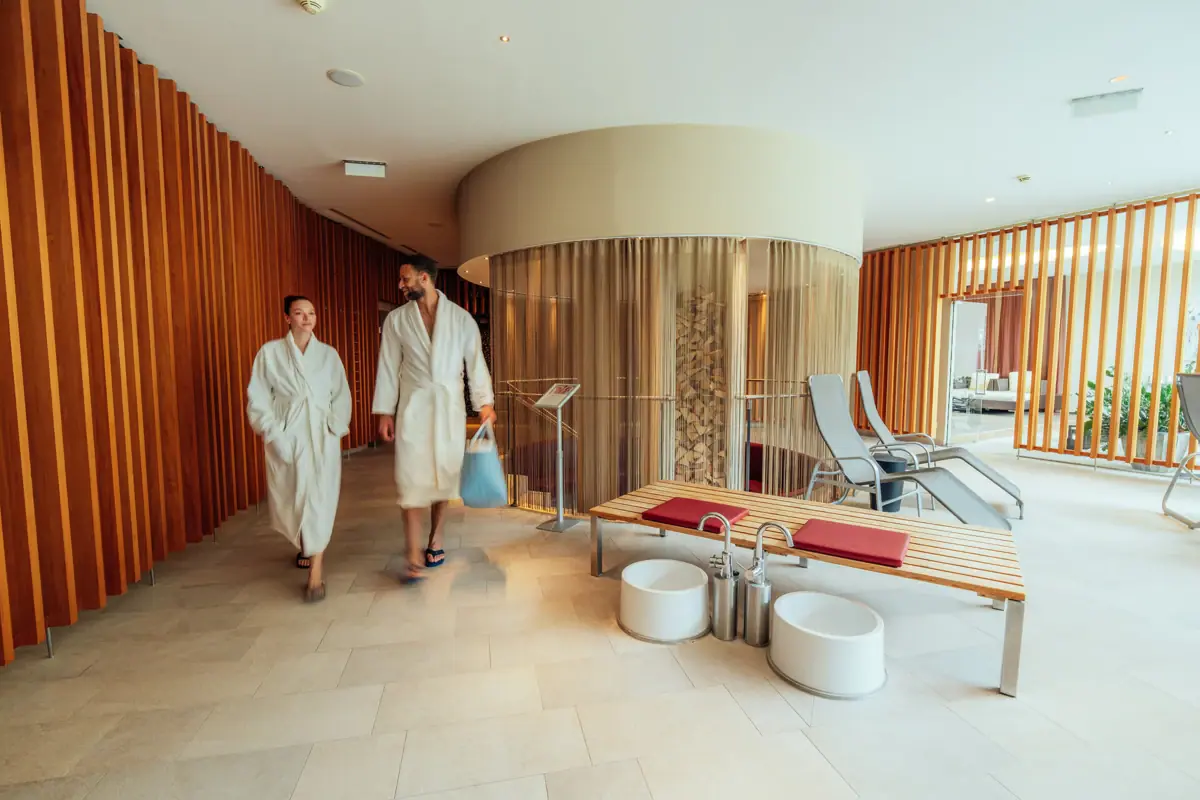 SPA-Bereich Ein Mann und eine Frau in weißen Bademänteln gehen in einem Raum.