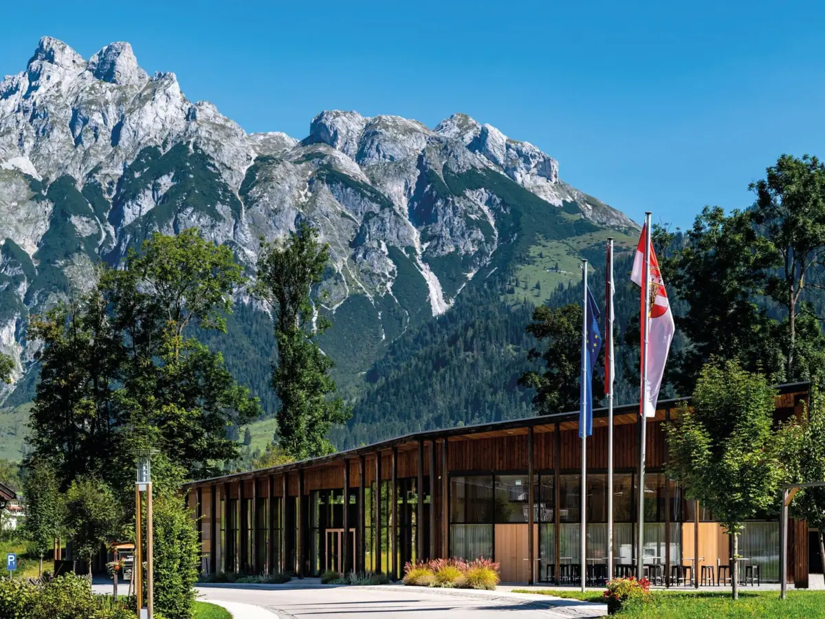 Tagungszentrum mit Flaggen vor Bergkulisse.