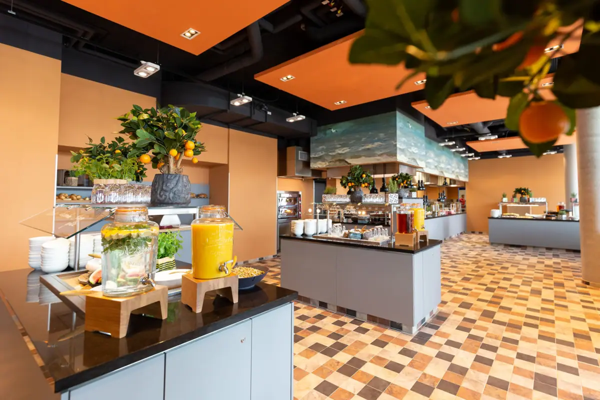 Frühstücksbuffet im JEDERMANNS Ein Raum mit orangefarbenen und gelben Getränken und Speisen auf einer Arbeitsplatte.