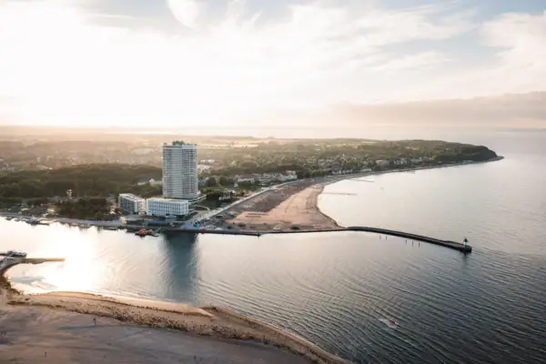 Travemünde von oben Ein Strand mit Wasser und einem Gebäude im Hintergrund.