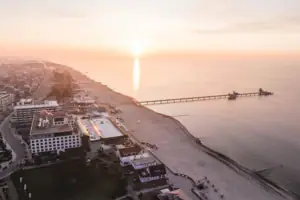 Strand mit einem Pier und Gebäuden bei Sonnenuntergang.