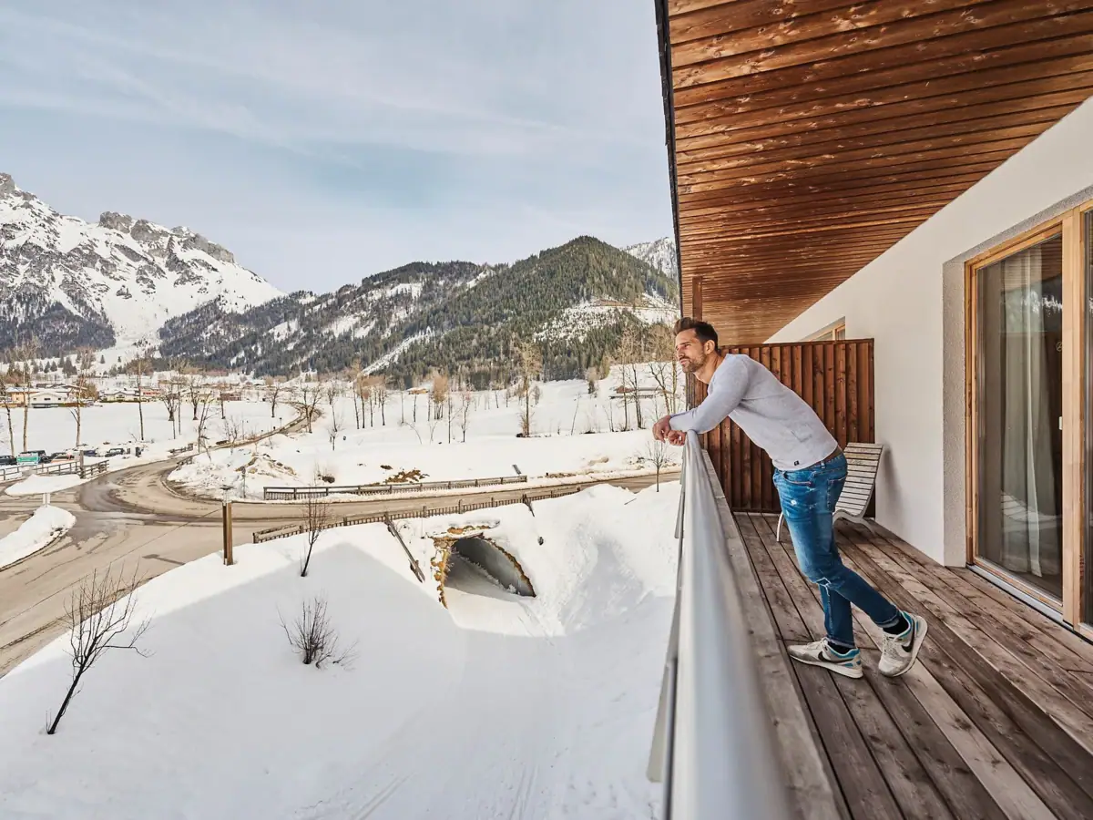 Ein Mann steht auf einem verschneiten Balkon.