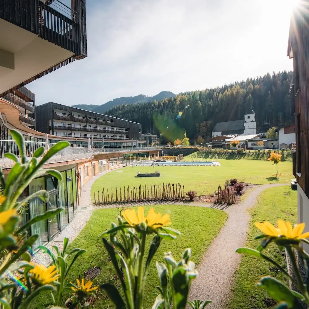 Grasfläche mit Gebäuden und Bäumen im Hintergrund